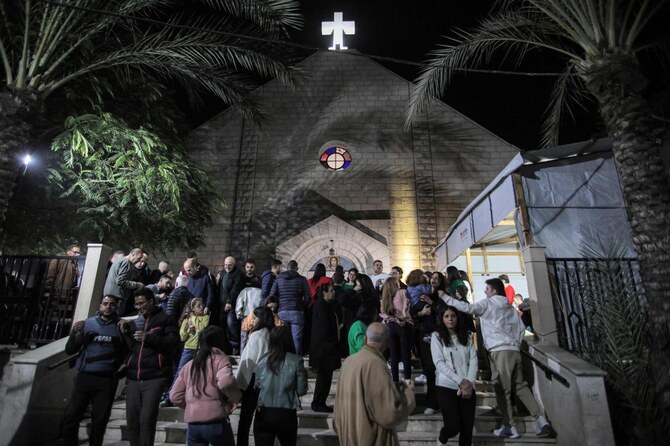 2024年12月24日、ガザ市のザイトゥーン地区にあるローマカトリック聖家族教会で、クリスマスイブのミサを終え、外を歩く参拝者たち。(AFP=時事)