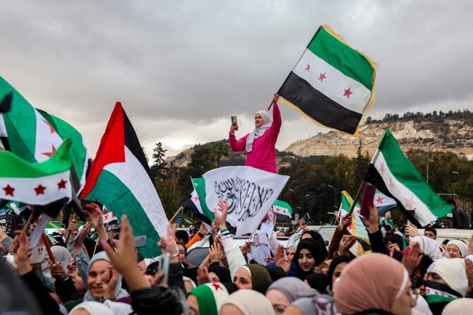金曜日、ダマスカスで行われたアサド大統領失脚を祝うデモで、独立時代のシリア国旗を振る人々。(AFP)