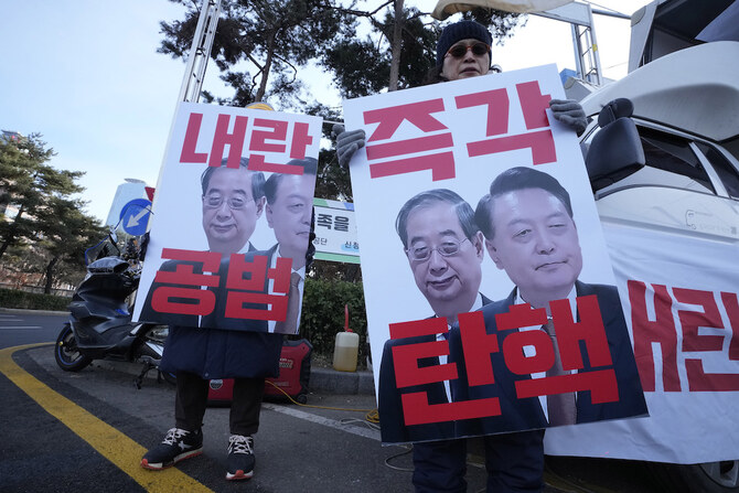 2024年12月27日、韓国・ソウルで開かれた集会で、弾劾された尹錫烈大統領（右）とハン大統領代行のバナーを掲げるデモ参加者たち。(AP)