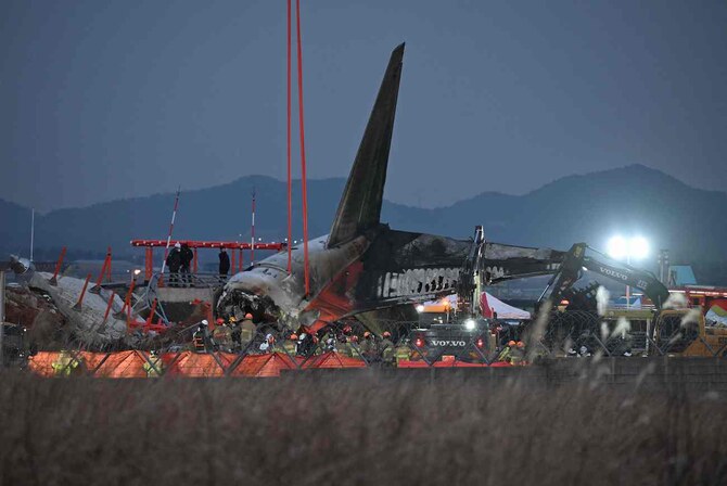 2024年12月29日、全羅南道の務安国際空港で、済州航空のボーイング737-800シリーズ機が墜落・炎上した現場付近で作業する消防士たち。(AFP=時事)