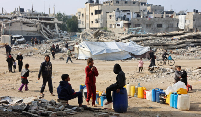 2025年1月11日、イスラエルとハマスの戦闘が続く中、ガザ市の仮設避難民キャンプで、パレスチナ人の子どもたちが水を補給するためにコンテナの近くに列を作っている。(AFP＝時事）