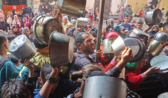 2025年1月11日、イスラエルとハマスの戦闘が続く中、ガザ市の仮設避難民キャンプで、パレスチナ人の子どもたちが水を補給するためにコンテナの近くに列を作っている。(AFP＝時事）