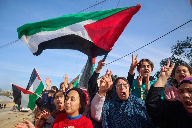 2025年1月19日、イスラエルとハマス間の停戦合意後、ガザ地区南部のラファに帰還した避難民パレスチナ人が国旗を振っている。(AFP＝時事）
