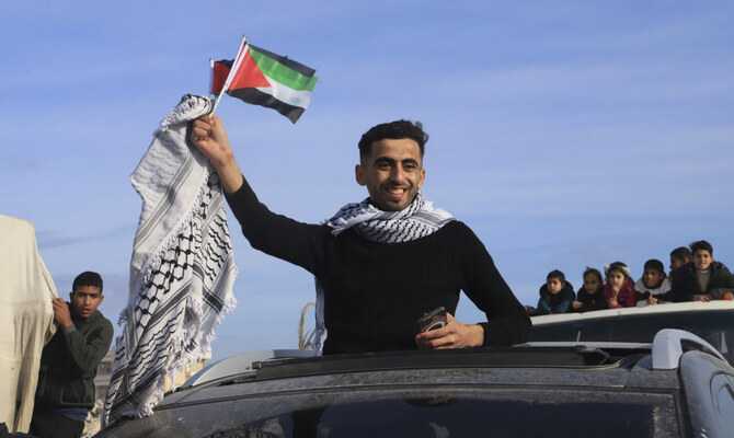 イスラエルとハマス間の停戦合意発効後、ラファに帰宅した男性がパレスチナ国旗を振っている(2025年1月19日、ガザ地区ラファ)。(AP)