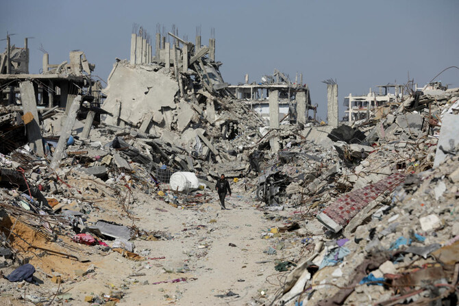 2025年1月29日、ガザ地区北部のジャバリア難民キャンプで、イスラエルの攻撃で破壊された家屋や建物の瓦礫の中を歩くパレスチナ人。(ロイター）