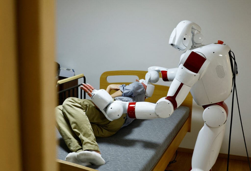 人工知能(AI)駆動ヒューマノイドロボットAIRECが、早稲田大学の研究室で研究者とオムツ交換や床ずれ予防のための動作を実演している(2025年2月17日、日本・東京)。(REUTERS/Kim Kyung-Hoon)