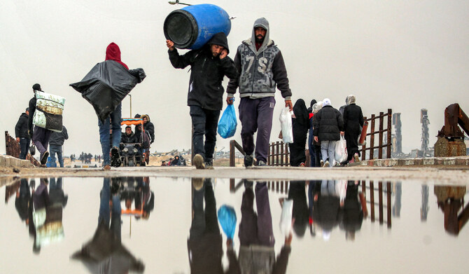 2025年2月10日、イスラエルとハマスの間で停戦が合意される中、避難民が故郷に戻る中、ガザ地区中央部のガザシティとヌセイラットの間を横切るアル・ラシッド通り沿いのワディ・ガザ橋を荷物を持って歩く人々。(AFP＝時事）