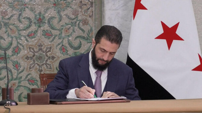 2025年3月13日、シリアのダマスカスで、シリアの法律専門家委員会が提出した憲法草案に署名するアフメド・アル・シャラア暫定大統領。(ロイター)