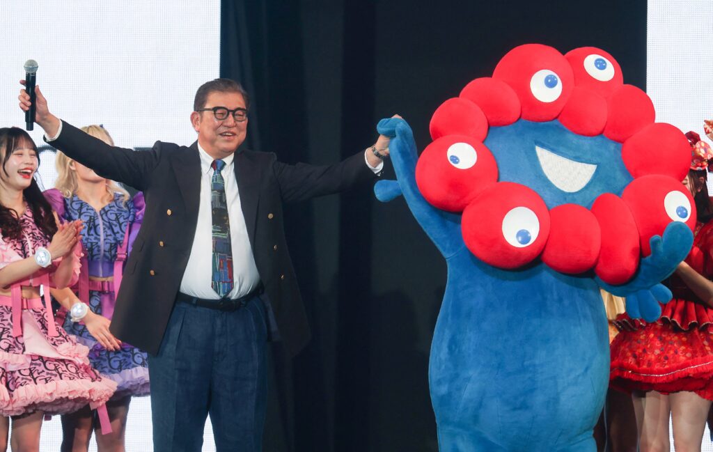 ガールズグループのメンバーに囲まれながら、石破茂首相が東京ガールズコレクションにサプライズ登場した。(AFP)
