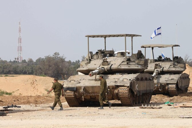 2025年3月6日、イスラエル軍兵士がガザ地区とのイスラエル南部国境付近の戦車前を通り過ぎる。(AFP)
