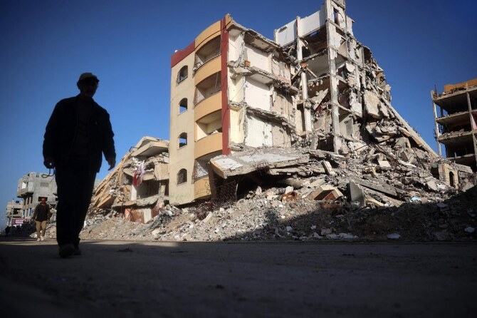 2025年3月14日、ガザ地区中心部のヌセイラット難民キャンプの戦災地区を歩くパレスチナ人。(AFP)