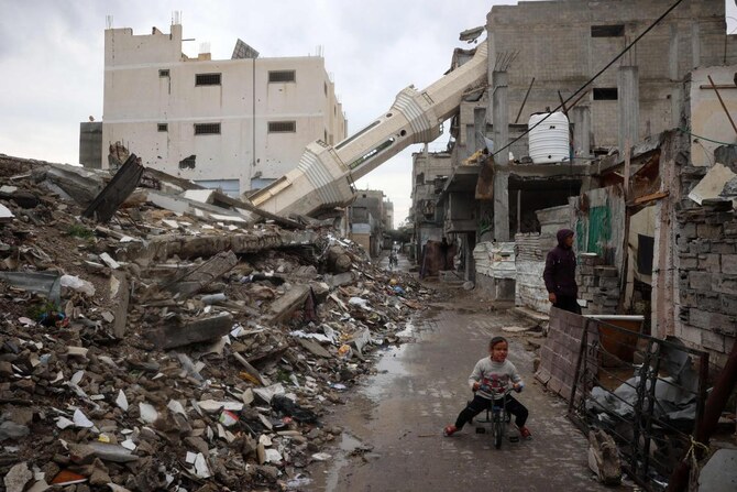 2025年3月7日、ガザ地区中央部のヌセイラット難民キャンプで、イスラム教の聖なる断食月ラマダンの間、破壊されたモスクの倒壊したミナレットの近くで自転車に乗るパレスチナ人の子供。(AFP)