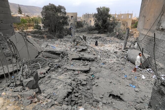2025年3月24日、イエメンのフーシ派が掌握する首都サヌアで米軍が空爆を行ったとされる現場で、倒壊した建物の瓦礫の間に立つ男性。(AFP)