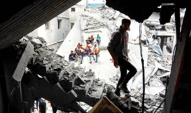 ガザ市シェジャイヤ地区の住宅街で、イスラエル軍の空爆を受け、がれきの中を歩く男性。(AFP=時事)