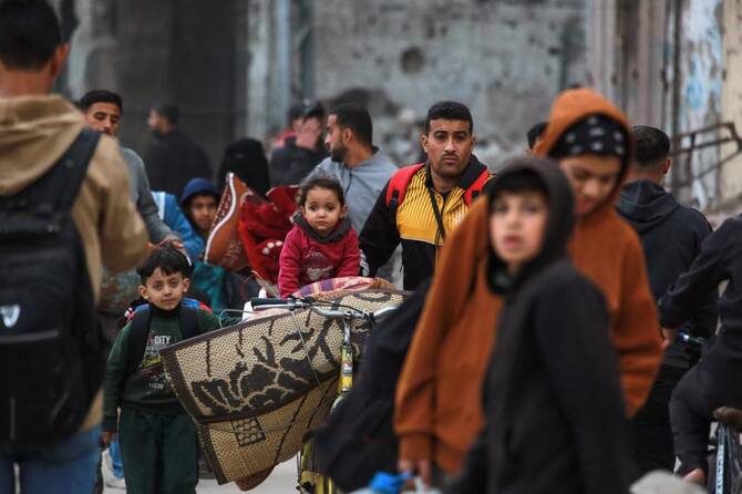 パレスチナ人が、2025年4月11日のイスラエルの退去命令に従い、ガザ市の東部の近隣地域からガザ市に到着し、持ち物を運んでいる。（AFP）