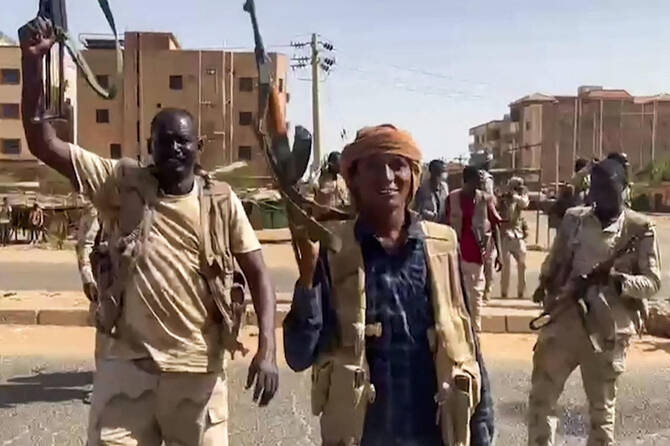 この画像は、2023年4月23日にスーダンの準軍事組織即応支援部隊(RSF)が公開した配布用ビデオ映像からキャプチャしたもので、戦闘員たちがハルツームの東ナイル地区の通りを横断しながら突撃銃を振り回している。(AFP)