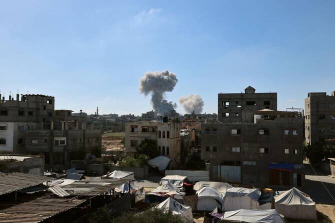 木曜日、ガザ地区中央部のヌセイラット難民キャンプから撮影された、イスラエルによる空爆の際に背景に立ち込める煙。(AFP=時事)