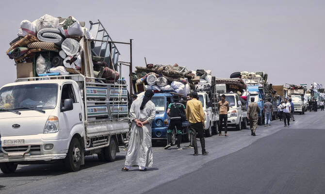 2025年5月18日日曜日、シリアのカフル・シジナ北の高速道路で、シリア・トルコ国境近くのアトメ・キャンプで5年以上過ごした後、彼らの村カフル・シジナへ向かう約60の避難民家族を乗せたトラックが高速道路に集まっている。(AP)