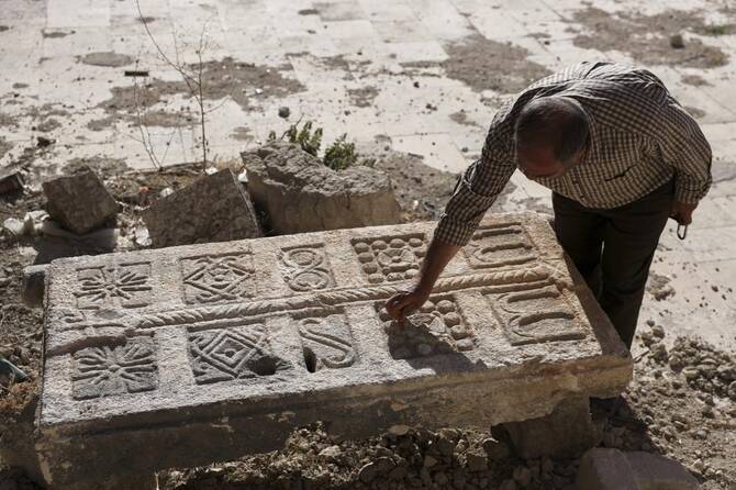2025年5月30日金曜日、シリアのマアル・アル・ヌマンにある博物館の庭で、警備員が刻まれた石を検査している。この石は、1500年以上前と推定されるビザンチン時代の地下墓地で、戦争で損傷した家の再建工事中に建設業者が発見し、博物館に運ばれたもの。(AP)