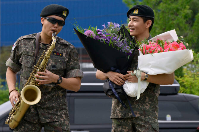 2025年6月10日、18カ月の韓国兵役を終えて、春川にある屋外スポーツ施設で、K-POPボーイズグループ「BTS」のメンバー、RM(左)がサックスを演奏し、Vが見守る。AFP)