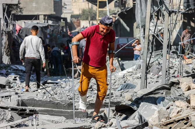 金曜日にガザ地区北部のジャバリアで、イスラエル軍の攻撃を受けて、男性が松葉杖をついて瓦礫の中を歩いている。(AFP)