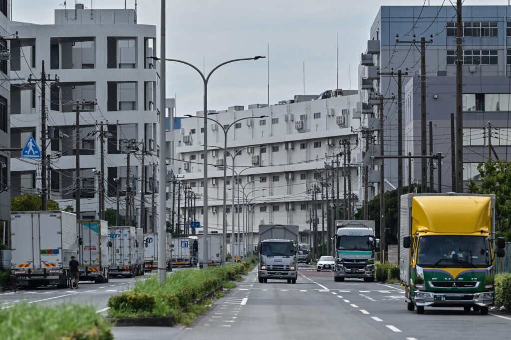 2024年9月4日に撮影されたこの写真は、神奈川県川崎市の工業地帯にあるガソリンスタンドと長距離ドライバーが利用するコンビニエンスストアのトラックストップの近くをトラックが並ぶ様子。(AFP)