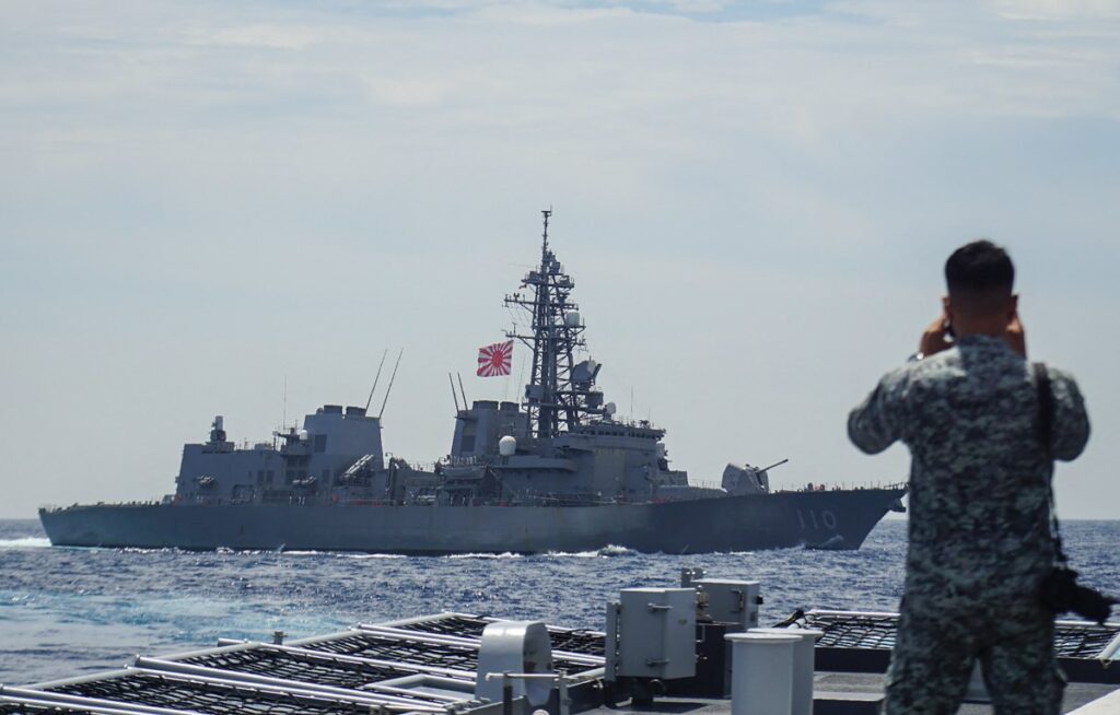 2025年6月14日、南シナ海で行われた合同海上演習で、フィリピン海軍の隊員が海上自衛隊の駆逐艦「高波」を見上げる。(AFP)
