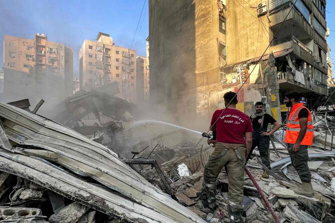 2025年6月6日、ベイルート南郊のカエム地区で、イスラエル軍による夜間の空爆で炎上した建物を消火する民間防衛隊員と消防隊員。(AFP)