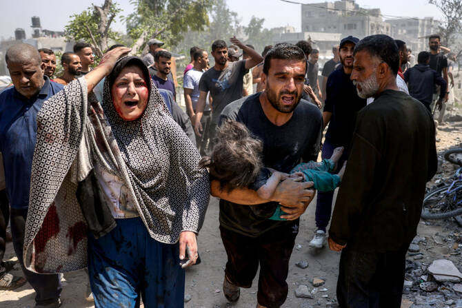 2025年6月9日、ガザ地区北部のジャバリア、サフタウィ地区で、イスラエル軍の攻撃を受けたシャヒーン家の家屋から、負傷した子供を持ち出す男性を見るパレスチナ人女性。(AFP)