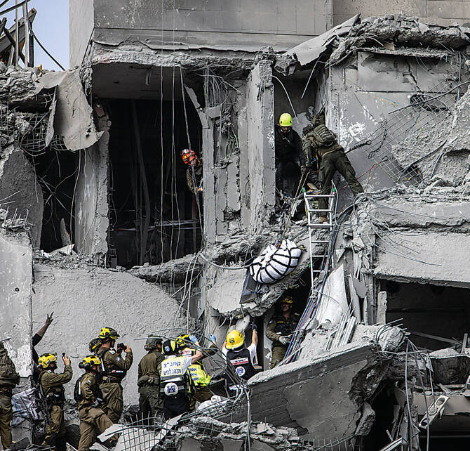 2025年6月24日、イスラエル南部のベエルシェバで、イランのミサイルが直撃した建物の瓦礫の中から、イスラエルの救急隊員と治安部隊が犠牲者を捜索している。(AFP)