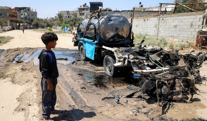2025年7月14日、ガザ地区中央部のパレスチナ難民キャンプ「ヌセイラット」で、イスラエル軍の爆撃によって破壊された移動式貯水タンクのそばに立つ少年。(AFP)