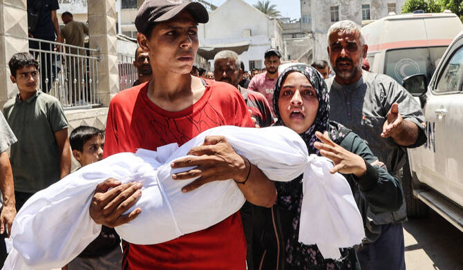 2025年7月13日、ガザ市のマーマダニ(バプテスト)病院で、イスラエルの空爆で死亡したパレスチナ人医師アフマド・カンディルの遺体を囲む同僚たち。(AFP=時事)