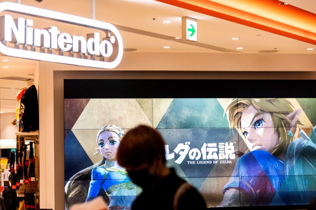 2022年2月3日、東京にある日本のゲーム大手、任天堂の店舗で、任天堂のゲーム「ゼルダの伝説」のキャラクターが映し出されたスクリーンの前を通り過ぎるフェイスマスクを着けた人。(AFP＝時事）