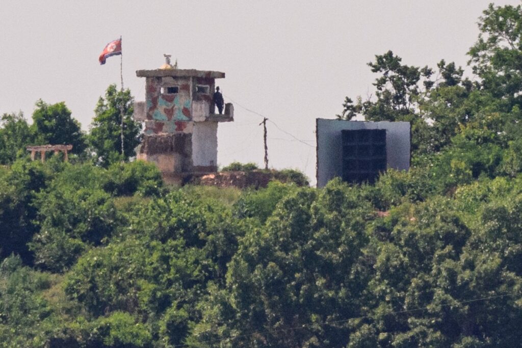 写真は2025年6月12日、坡州にある南北朝鮮を分断する非武装地帯(DMZ)近くの監視塔で、巨大な拡声器(右)の横に立って警備する北朝鮮の兵士。(AFP=時事)