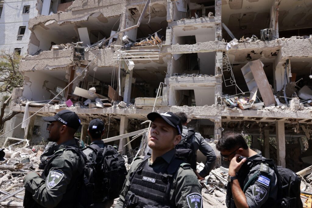 2025年6月22日、テルアビブでイランの空爆を受けた建物の前に集まるイスラエルの警察官。(AFP=時事)