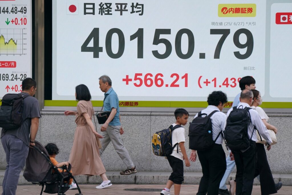 2025年6月27日、東京証券取引所で、日経平均株価が40,000円台となったことを示す電子掲示板の前を歩行者が歩いている。(AFP)