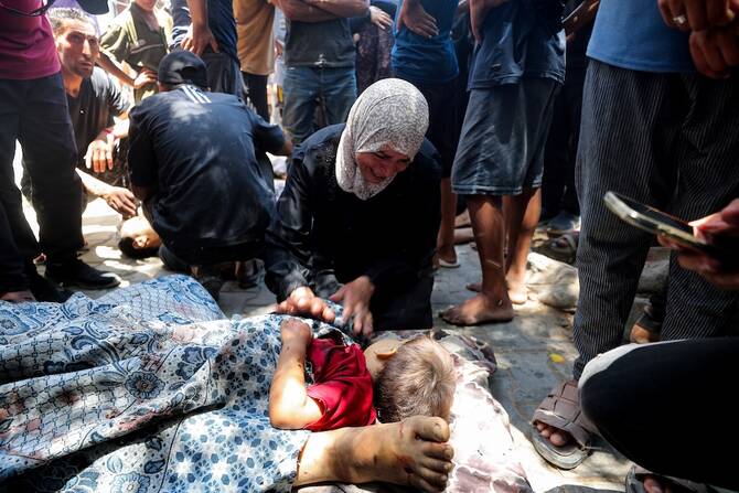 ガザ市のアル・シファ病院で、イスラエル軍の空爆で死亡した子どもの遺体のそばで悼むパレスチナ人女性。(ロイター)