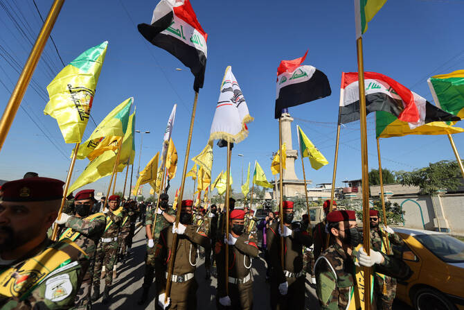 2023年12月4日、イラク北部での米軍の空爆で前日に死亡した武装勢力5人のバグダッドでの葬儀で、イラクと準軍事組織（アル・ヌジャバ、カタイブ・ヒズボラなど）の旗を掲げる戦闘員たち。(AFP/ファイル)