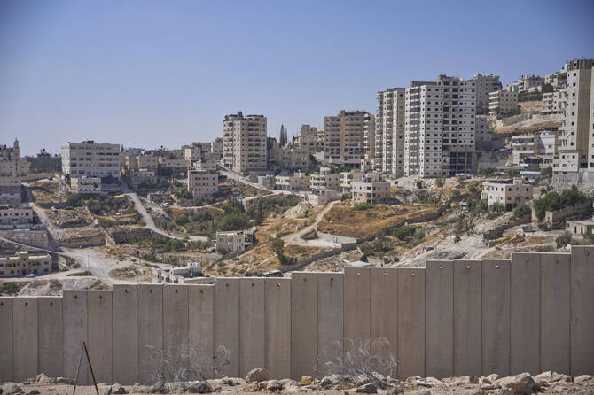 イスラエル政府がE1入植地開発プロジェクトの一環として住宅が建設されるとしているアル・エイザリヤのアラブ人居住区の隣にあるイスラエルの分離壁。(AP)