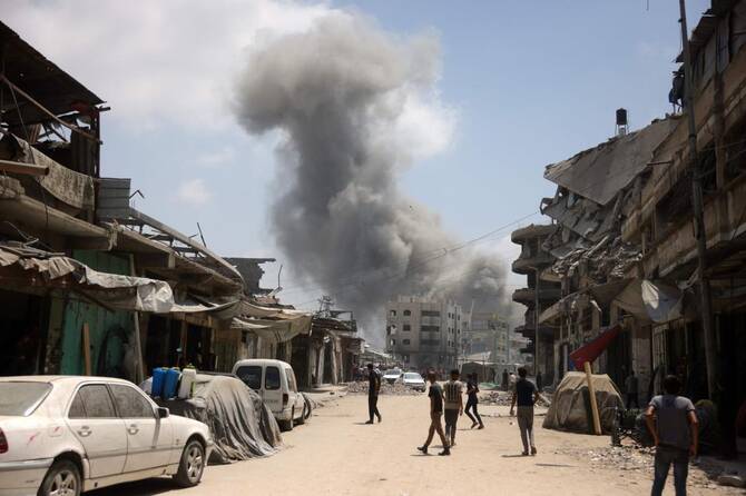 2025年8月8日、イスラエルによるガザ市南部アルザイトゥーン地区への攻撃中、立ち上る煙に見入るパレスチナ人。(AFP)