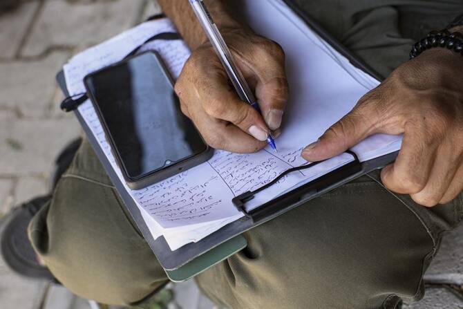 2025年8月21日、シリアのアフリンにある警察署で、シリア政府の治安部隊に入隊するサインをするクルド人男性。(AP)